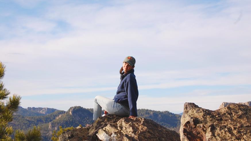 student on a rocky mountain overlooking horizon