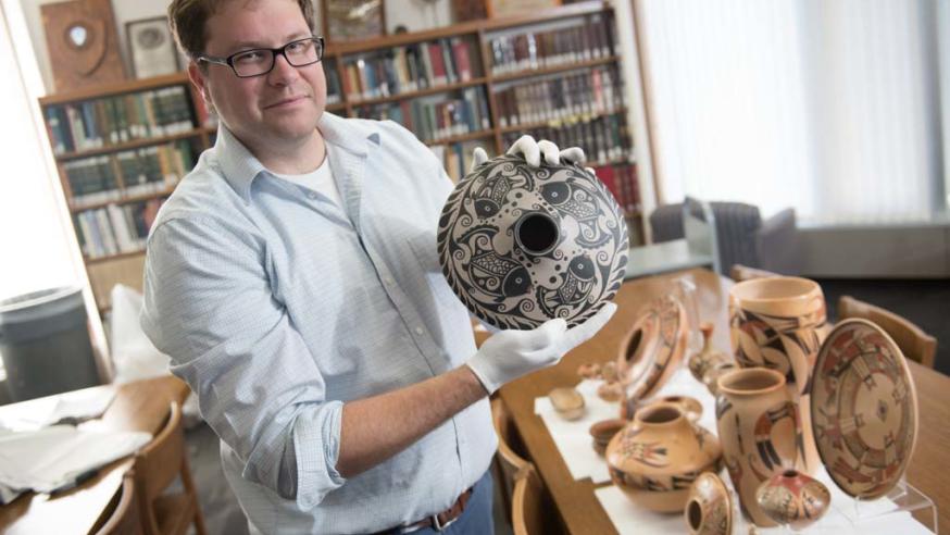 Greg Kocken in the archives with Native American pottery