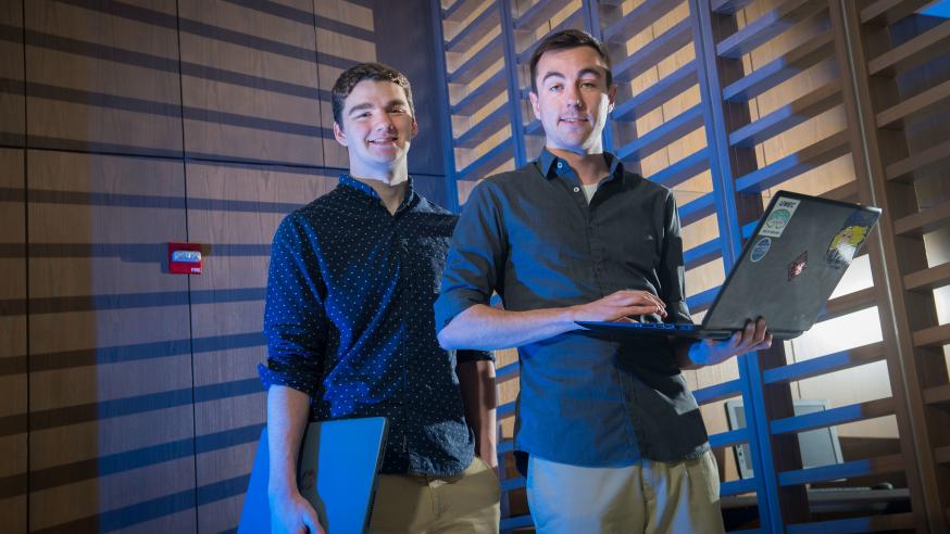 2 CS graduates with laptops