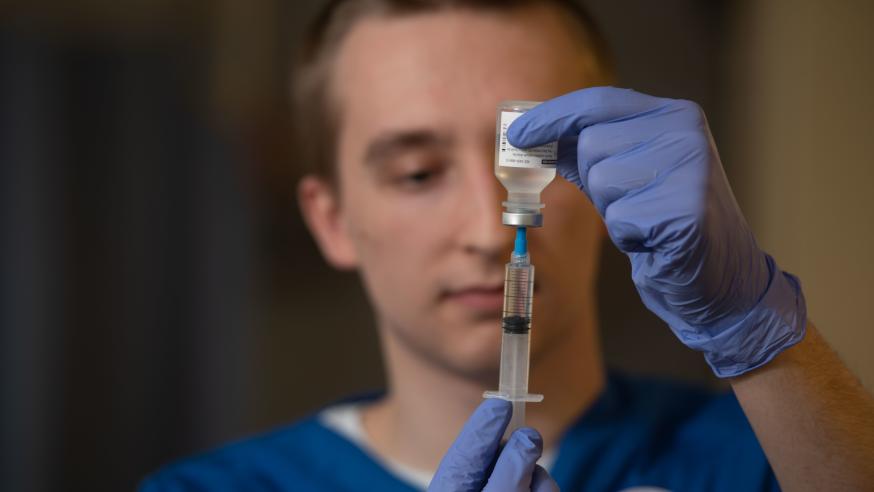 nursing student filling syringe from vial 