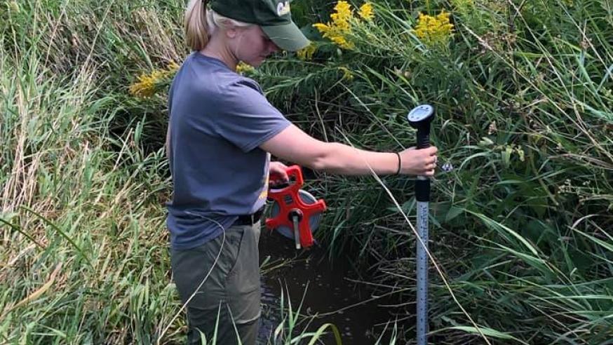 geology student testing water in campus creek
