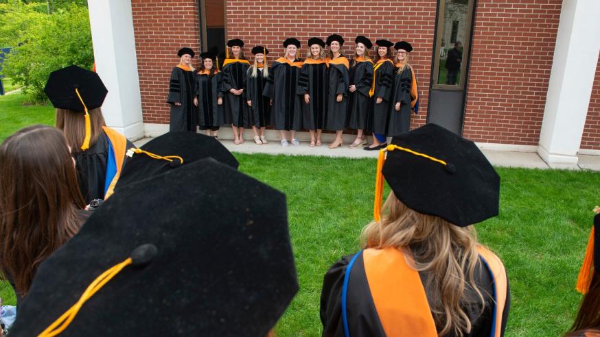 Nursing DNP grads 2022 outside CONHS in gowns and hoods