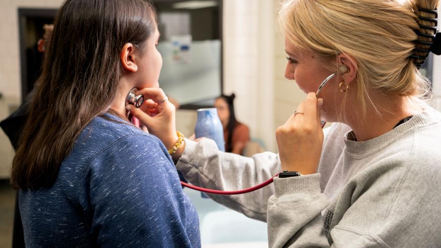 An image of two women in clinic, and using stethoscope to listen heartbeat