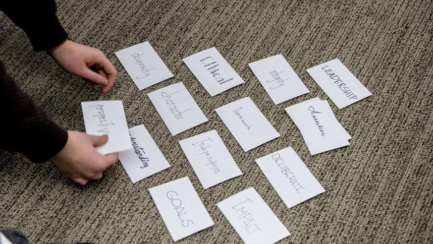 Index cards laid out in a pyramid with leadership qualities listed on each of them.