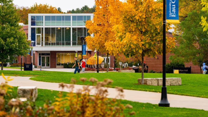 Students make their way through lower campus on a warm fall day. The Welcome Center can be seen in the background.