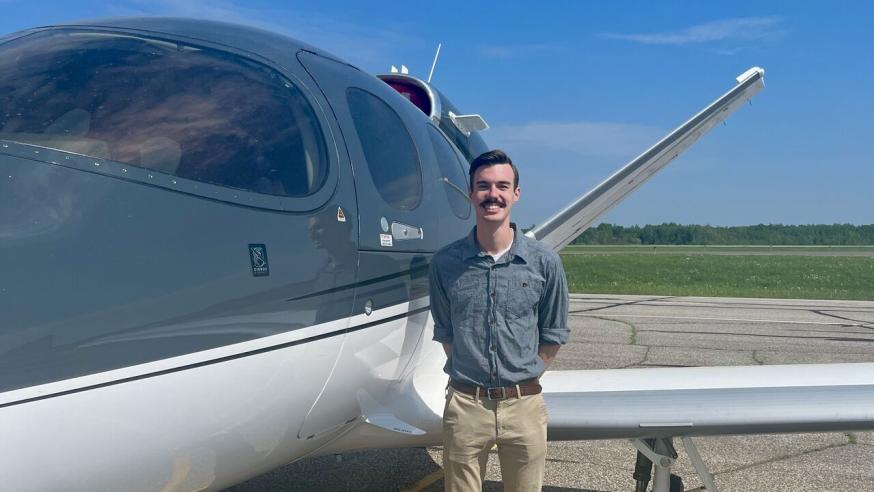 Supply Chain student, Brian Salinas, standing next to airplane during internship at Cirrus Aircrafts.