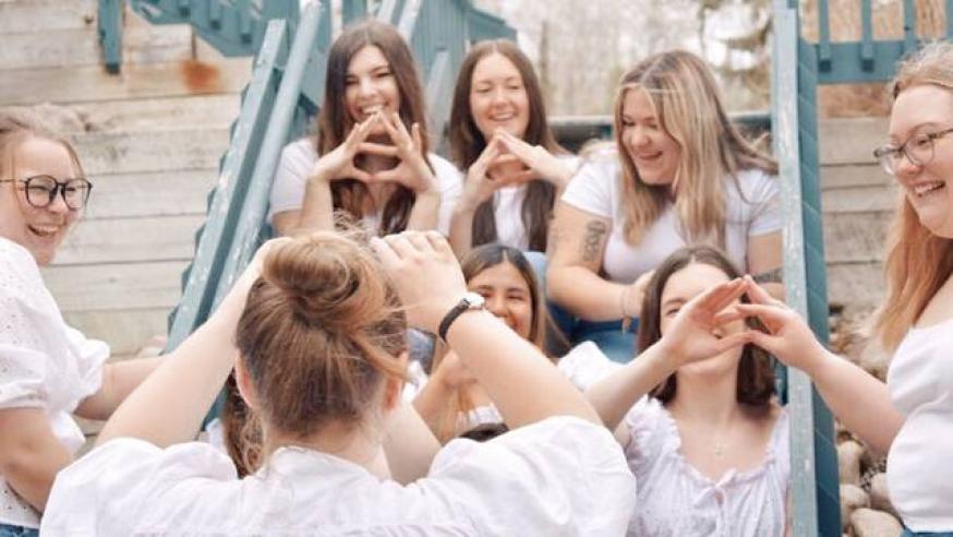 Members of a sorority making hand symbols that represent their organization