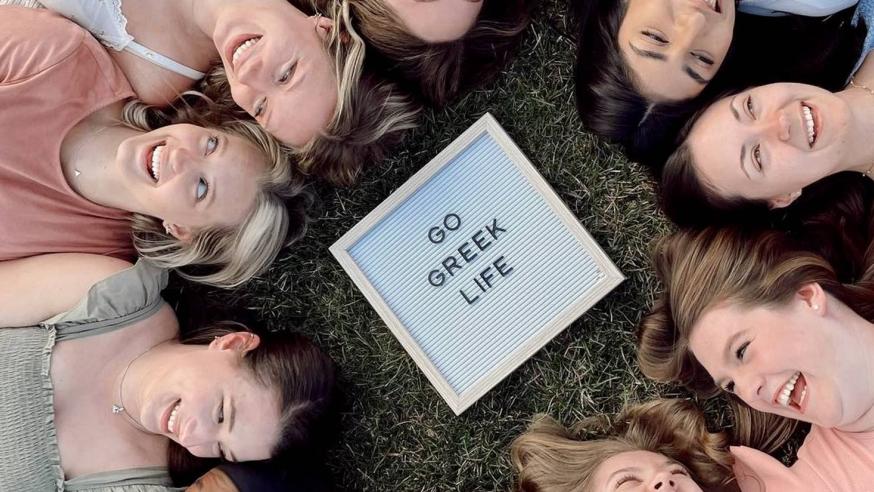 Students laying in a circle around a Go Greek Life sign in the middle