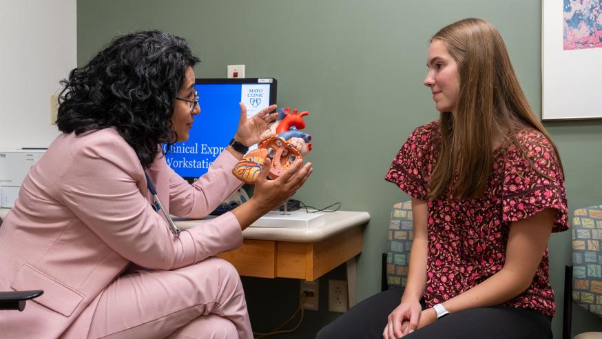 A student sits with a Mayo doctor in an exam room and looks at a 3D heart model.