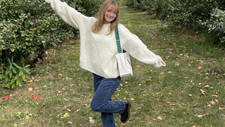 Sabrina Massie in a field, smiling with her arms out.
