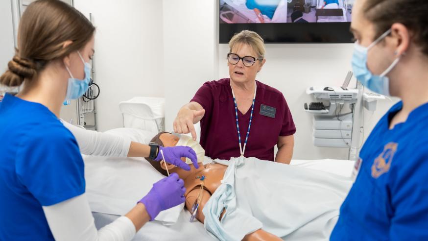 Nursing students learn from a health professional during a SIM lab.
