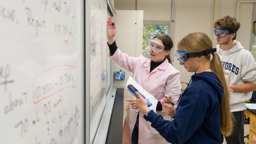 chemistry lab students and faculty at white board