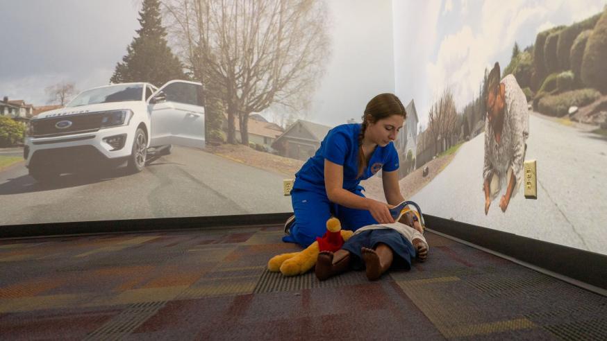 nursing student in AI simulation room with child mannequin on the floor