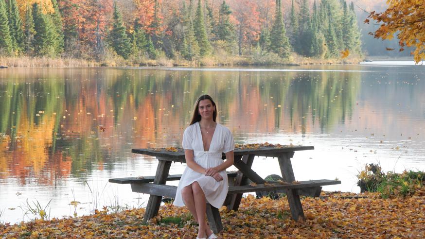 Student at a bench in front of a lake