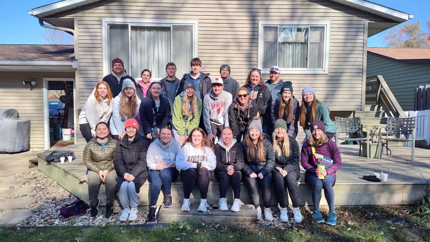 Kinesiology Club group poses for a photo in front of a house