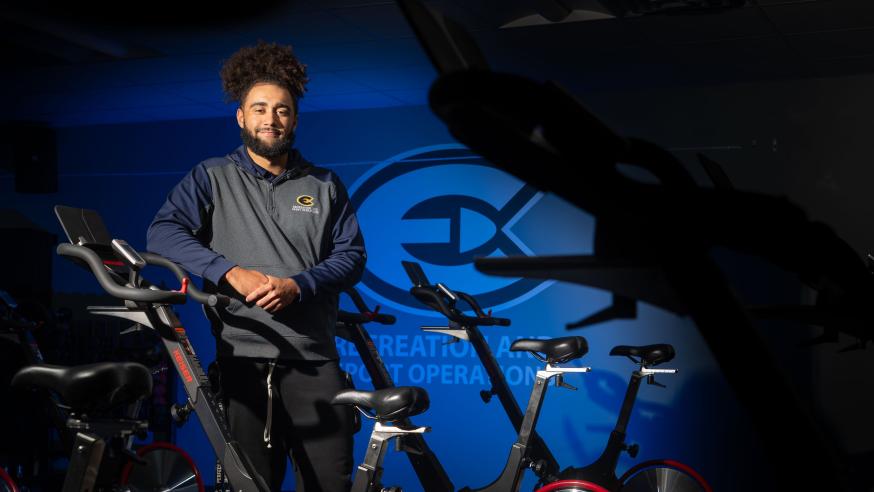 student recreation staff person in cycle studio leaning on a bike
