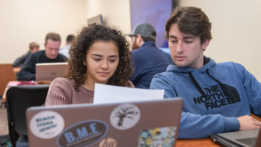 Two students look at an assignment together in class