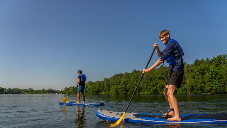 Two students paddleboard on the Chippewa River.