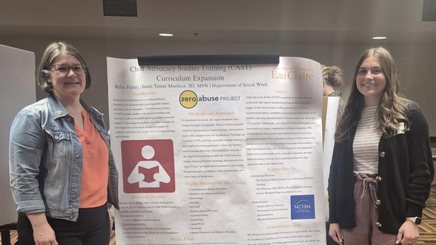 A student and faculty member pose on either side of a research poster