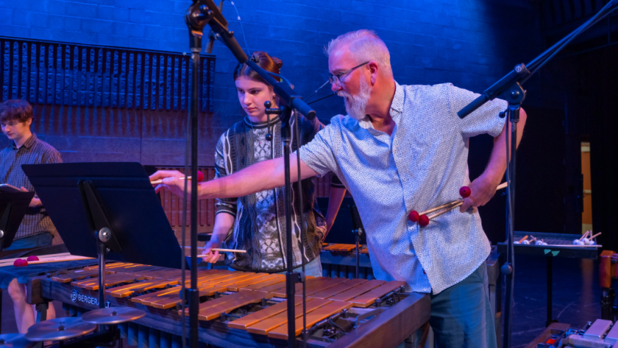 A music and theatre arts professor looks at sheet music with a student.