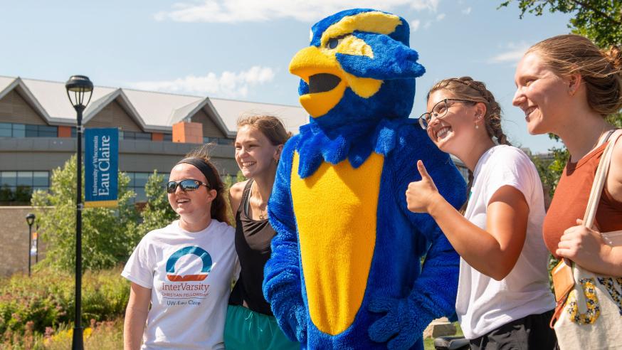 Blu taking a photo with a group of students smiling.