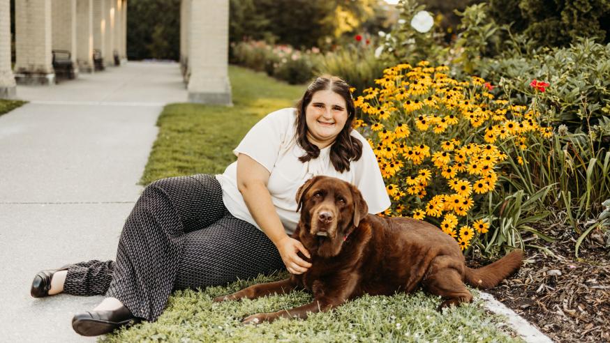 Megan Eilers lays in grass with her dog, Koda