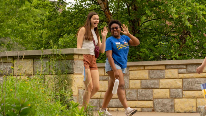 two students wave to camera during orientation