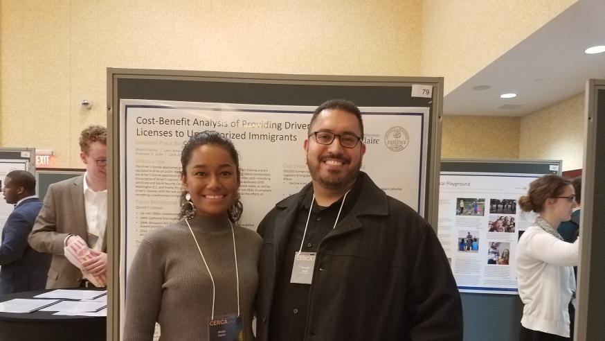 A student and faculty member stand in front of a research poster for Latin American and Latinx Studies.