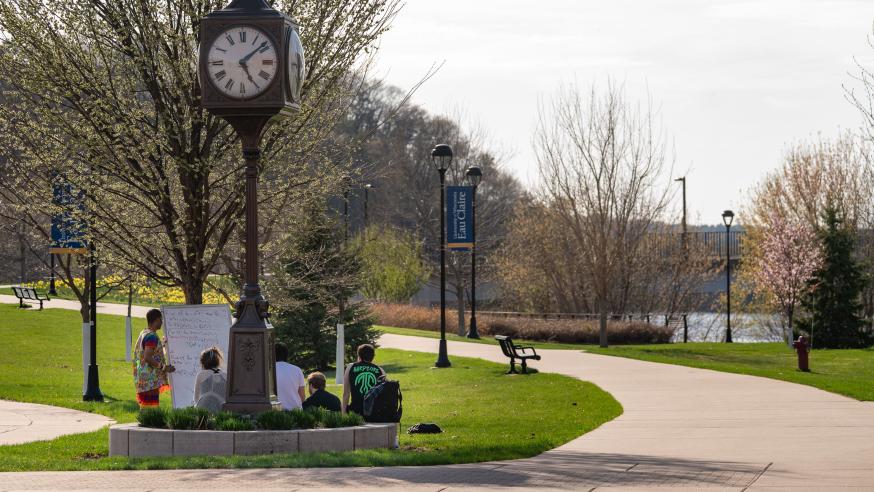 An outdoor class takes place under the clock tower on campus
