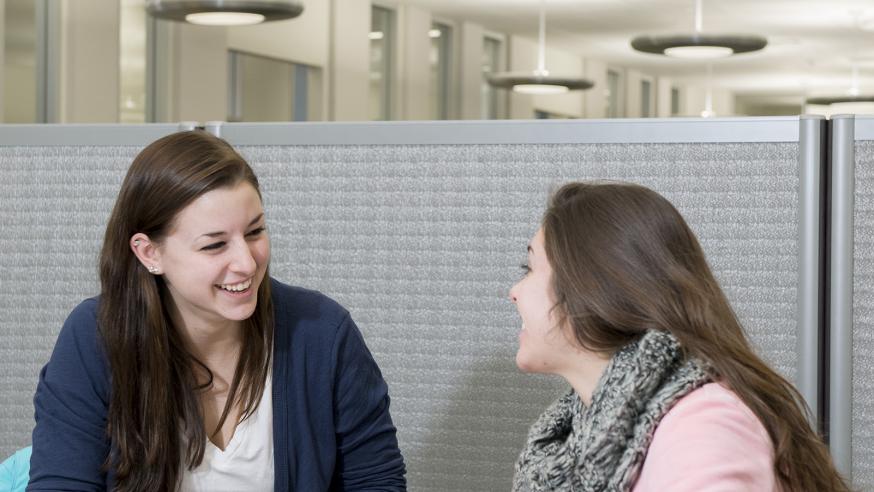 Two students sitting at a table laughing.