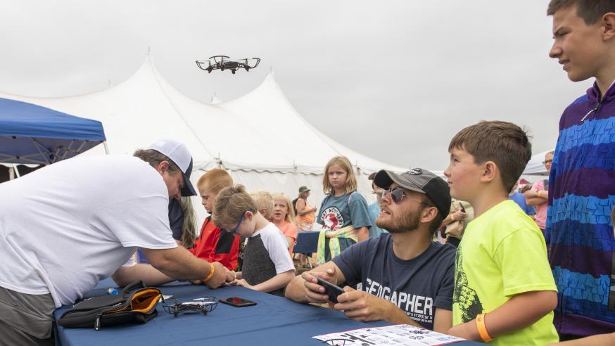 Kids and college student at toy drone table event
