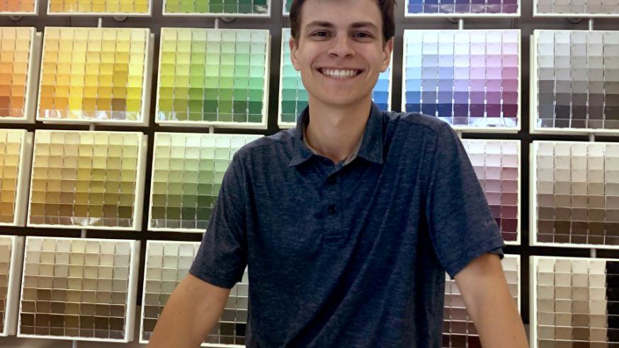 male student standing at counter in paint store