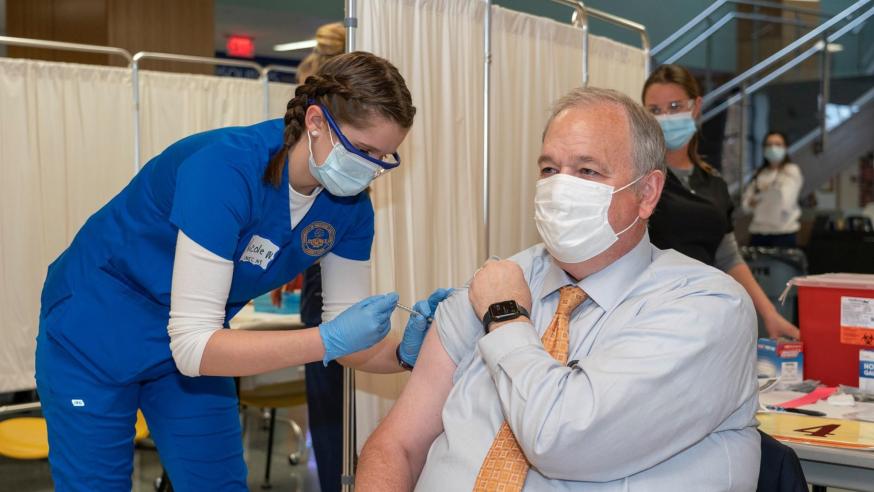 Chancellor Schmidt receiving a vaccination from a nursing student