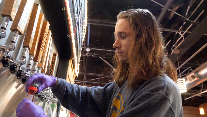 male student tapping beer in a local brewery