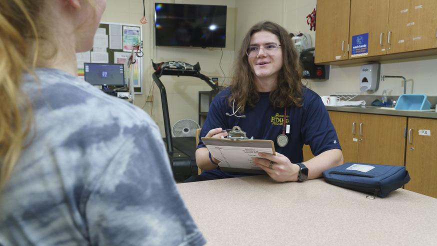 Male KINS student doing a vitals assessment for a female student