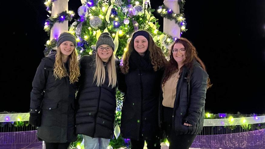 four girls in front of an outdoor Christmas tree