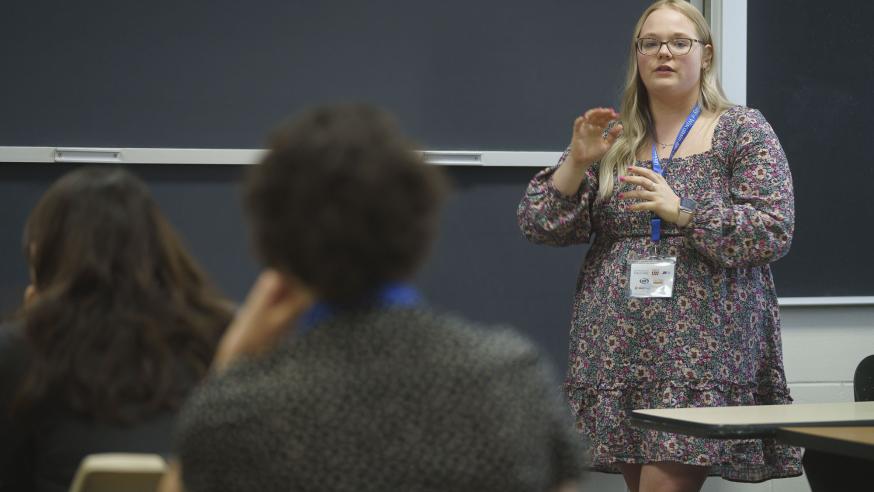 blond female student in front of a classroom at a white board