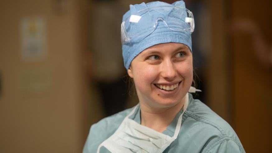 female student in full scrubs, mask down, smiling