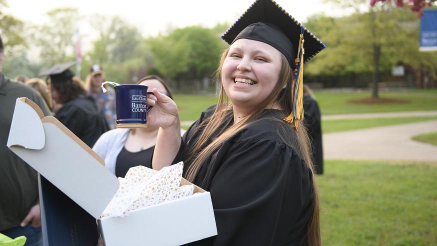female graduate holding a UW-Eau Claire Barron County coffee mug
