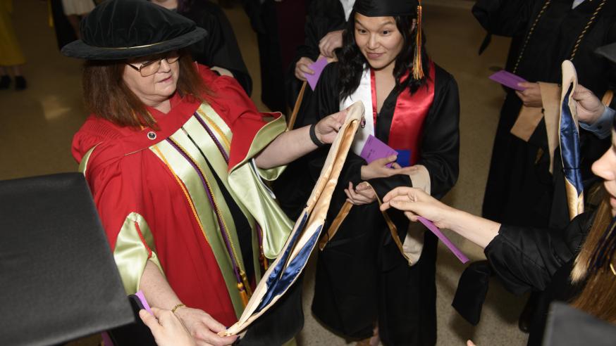 graduates and faculty backstage preparing for commencement