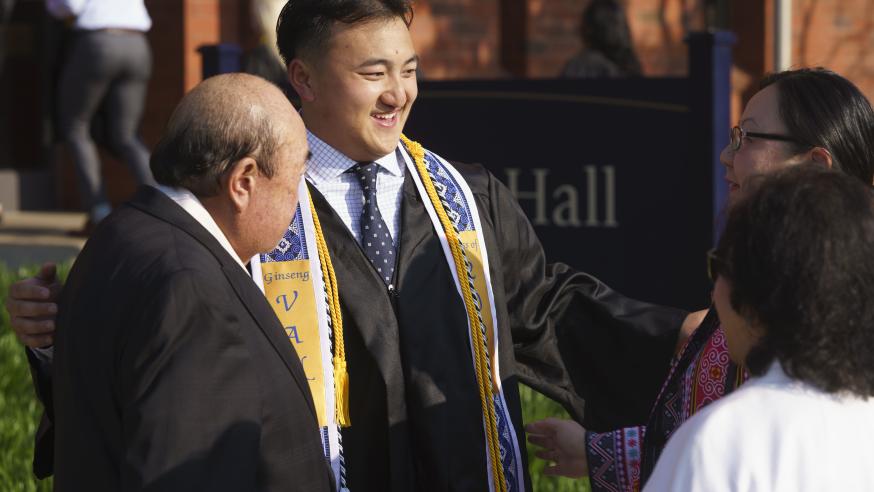 male student greeting family outside commencement ceremony