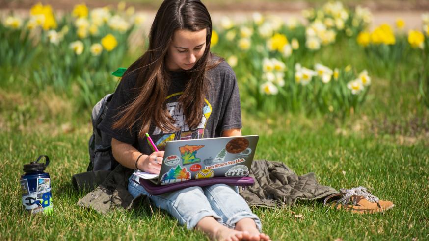student studying on campus mall , flowers in the background
