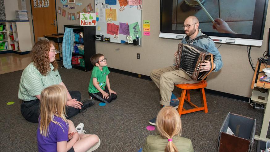 Two student teachers playing music for elementary students in a classroom