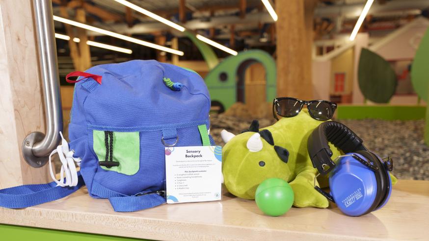 A backpack filled with items to help with sensory dysregulation, such as sunglasses and a weighted stuffed animal.