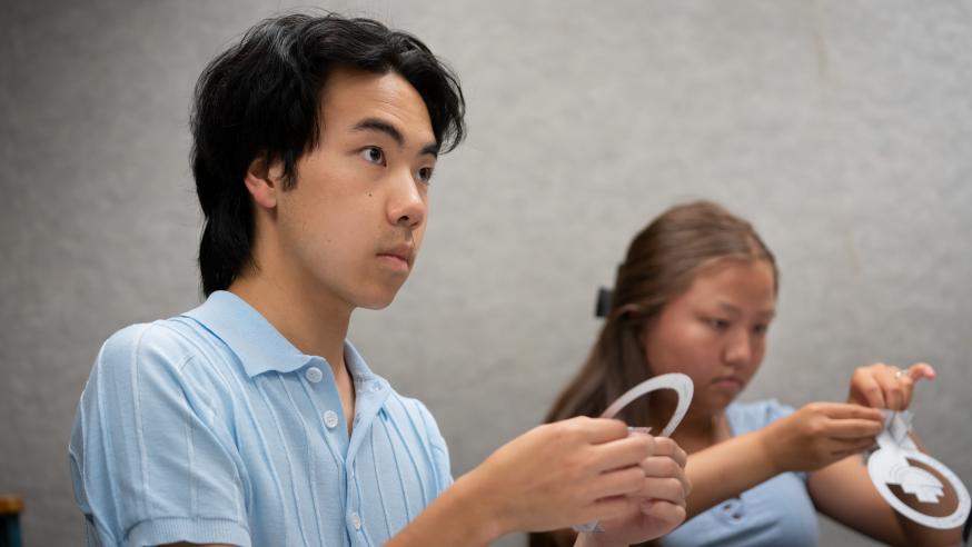 two students working with paper figures in a physics class