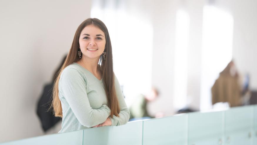 Annie Fochs in second floor of Centennial Hall, leaning on glass half wall.