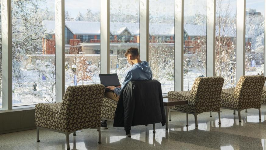 male student seating in the sunny 2nd floor window lounge of Centennial Hall