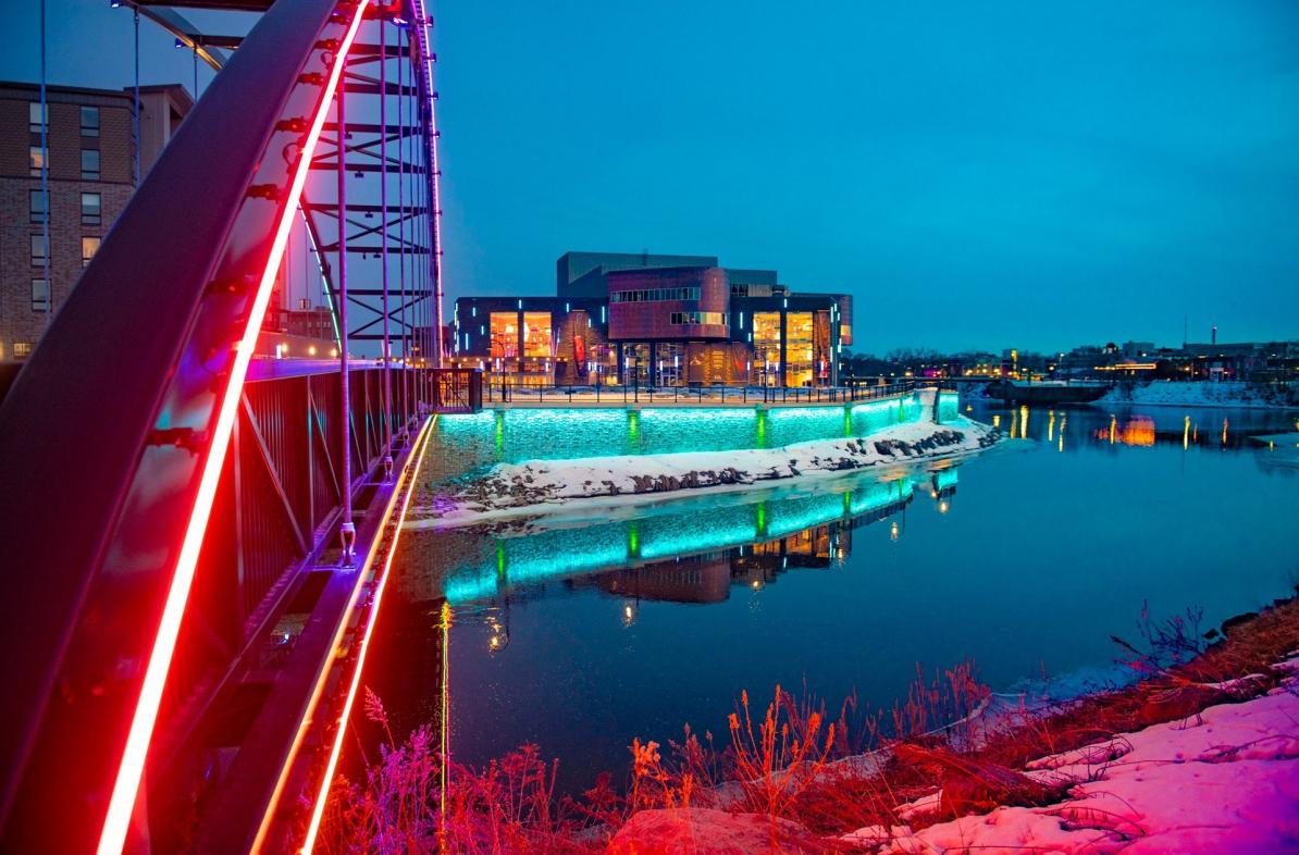 Pablo Center at sunset with colorful lights lighting up the bridge and river
