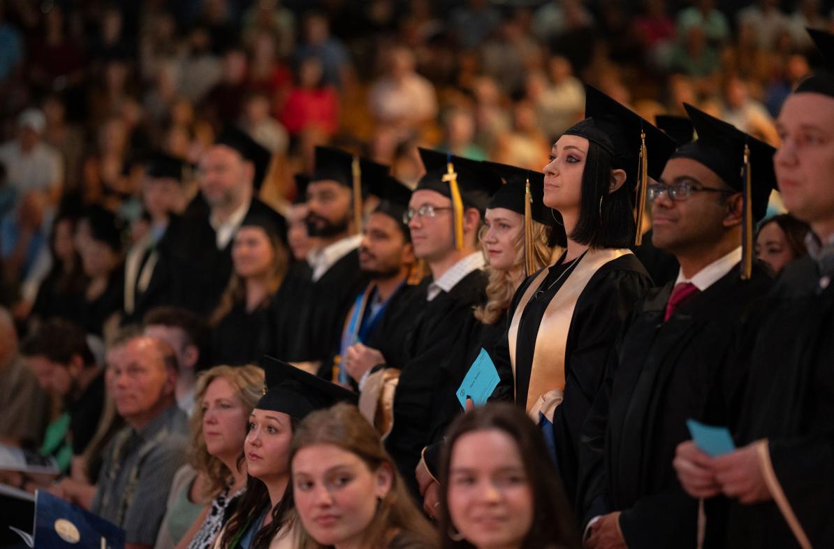 Graduates stand ready to receive their diploma