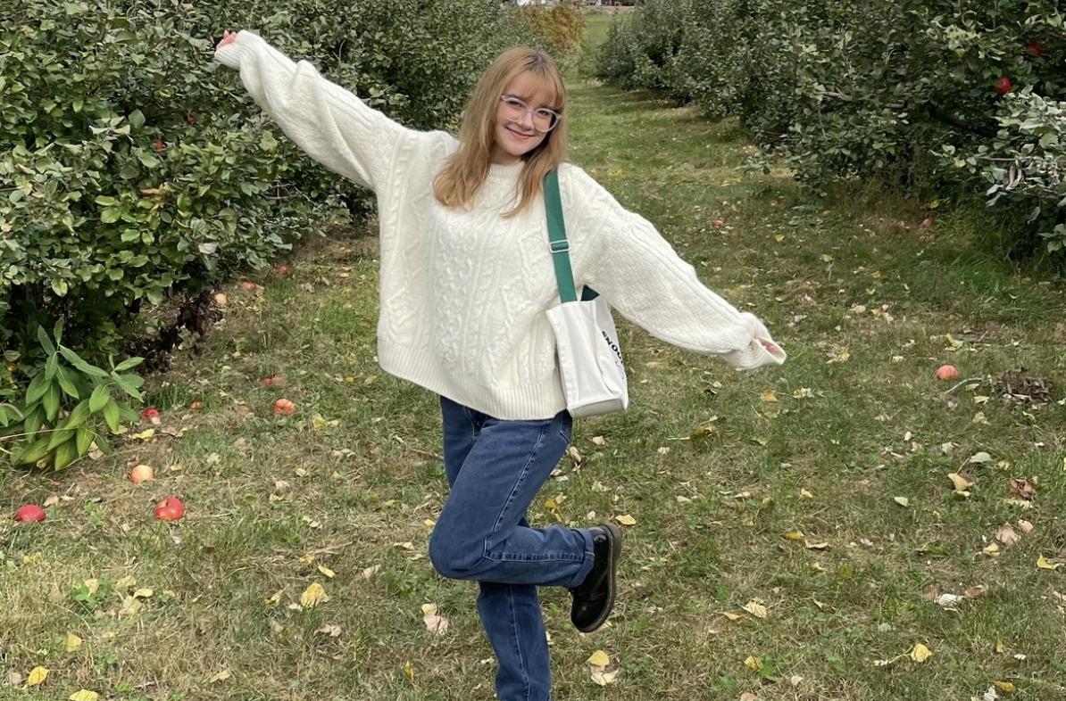 Sabrina Massie in a field, smiling with her arms out.